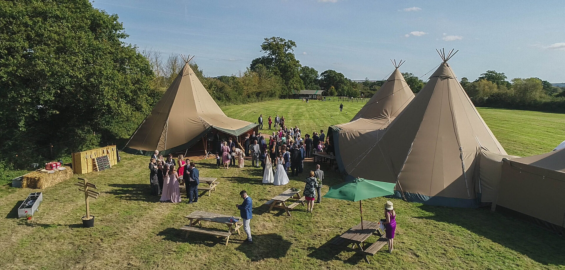 Wedding guests gathered around the tipis at Mill Farm
